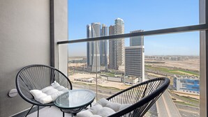 A balcony with two black wicker chairs and a glass table, overlooking a cityscape with modern buildings and a highway. - Silkhaus 15 Northside, Business Bay Dubai (Dubai)