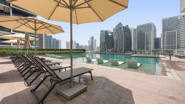 A rooftop pool area with lounge chairs and umbrellas, overlooking a cityscape with modern buildings. - Silkhaus 15 Northside, Business Bay Dubai (Dubai)