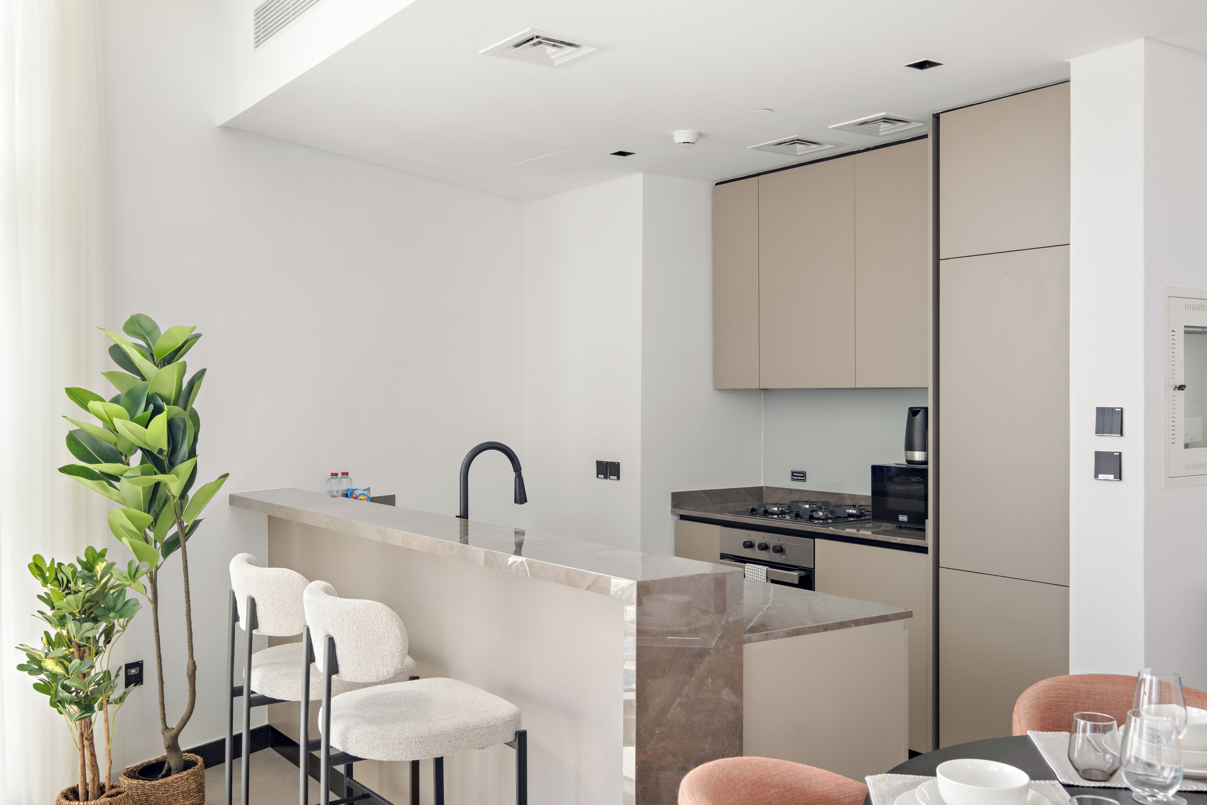 A modern kitchen with a central island, bar stools, and a dining table with chairs.