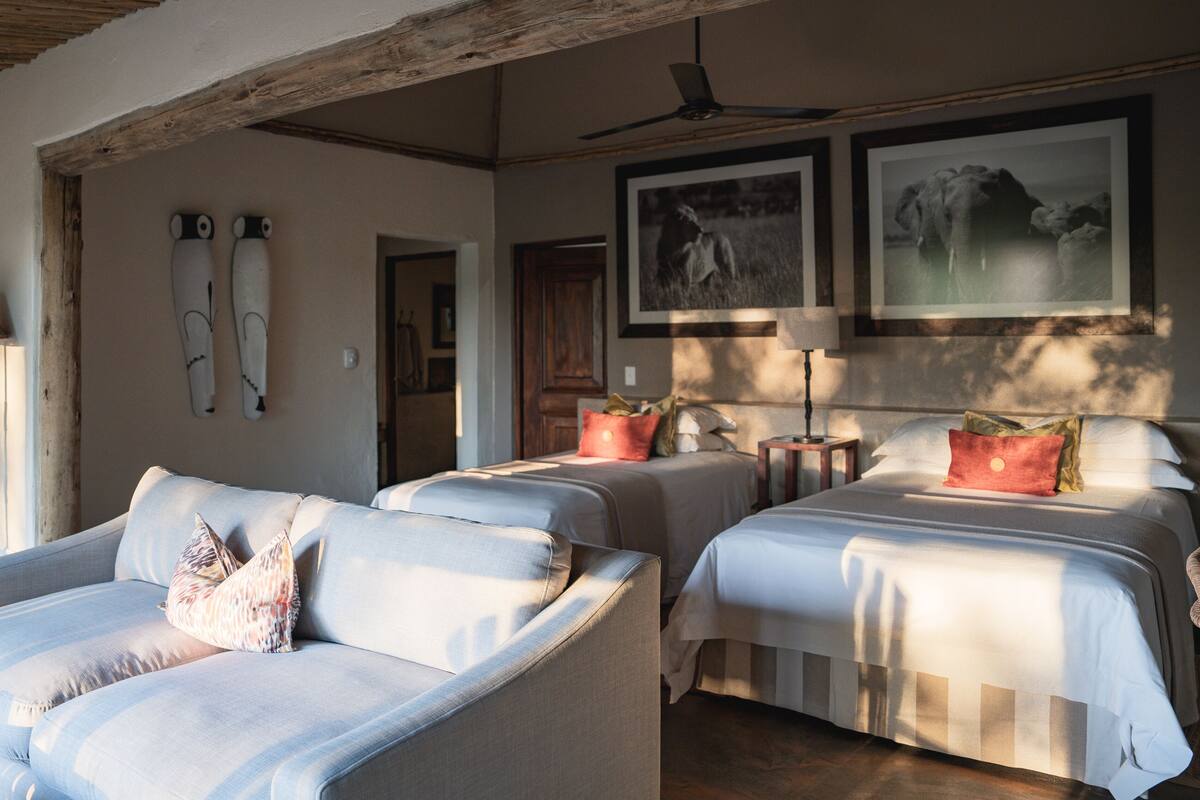A room with two beds, a sofa, and a ceiling fan.