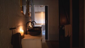 Un baño con poca luz, que incluye un lavamanos, un espejo y una toalla colgada en la pared.
