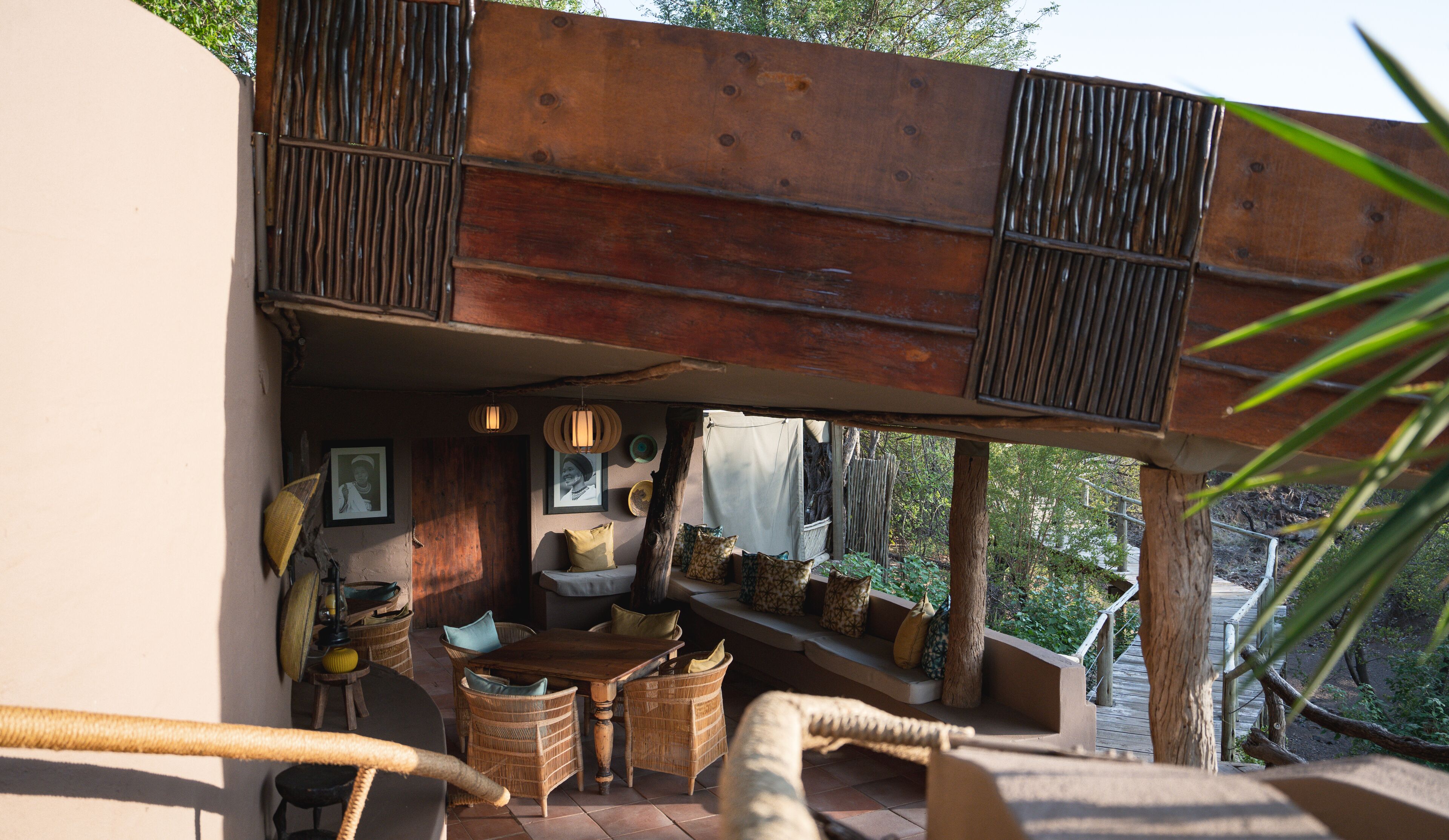 Un espace extérieur accueillant, aménagé avec des meubles en osier, une table en bois et offrant une vue sur la verdure environnante.