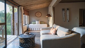 Una habitación con una cama, un sofá, una mesa redonda y vistas amplias a través de grandes ventanas.