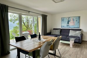 Un salon moderne avec une table à manger en bois, un canapé gris et un tableau accroché au mur.
