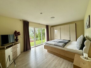 Quarto com cama, TV, escrivaninha e vista para o exterior.