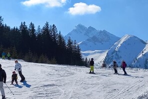 Pista de esquí nevada con esquiadores y una montaña al fondo.