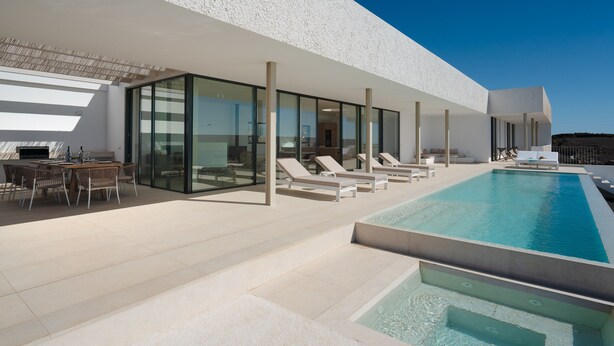A modern outdoor pool area with lounge chairs and a dining setup.