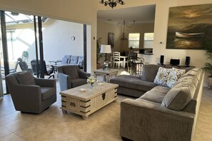 A living room with a sofa, armchairs, a coffee table, and a dining area with chairs and a table.