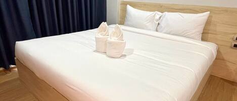 Una cama bien hecha con sábanas blancas y dos toallas dobladas encima.