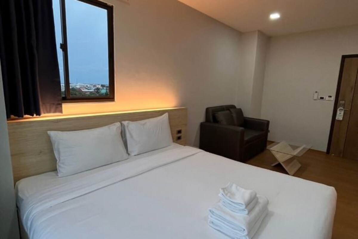 Habitación de hotel con cama, una silla y vista a la ciudad.