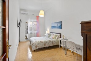 Un dormitorio con cama, mesita de noche, lámpara y un escritorio con silla.