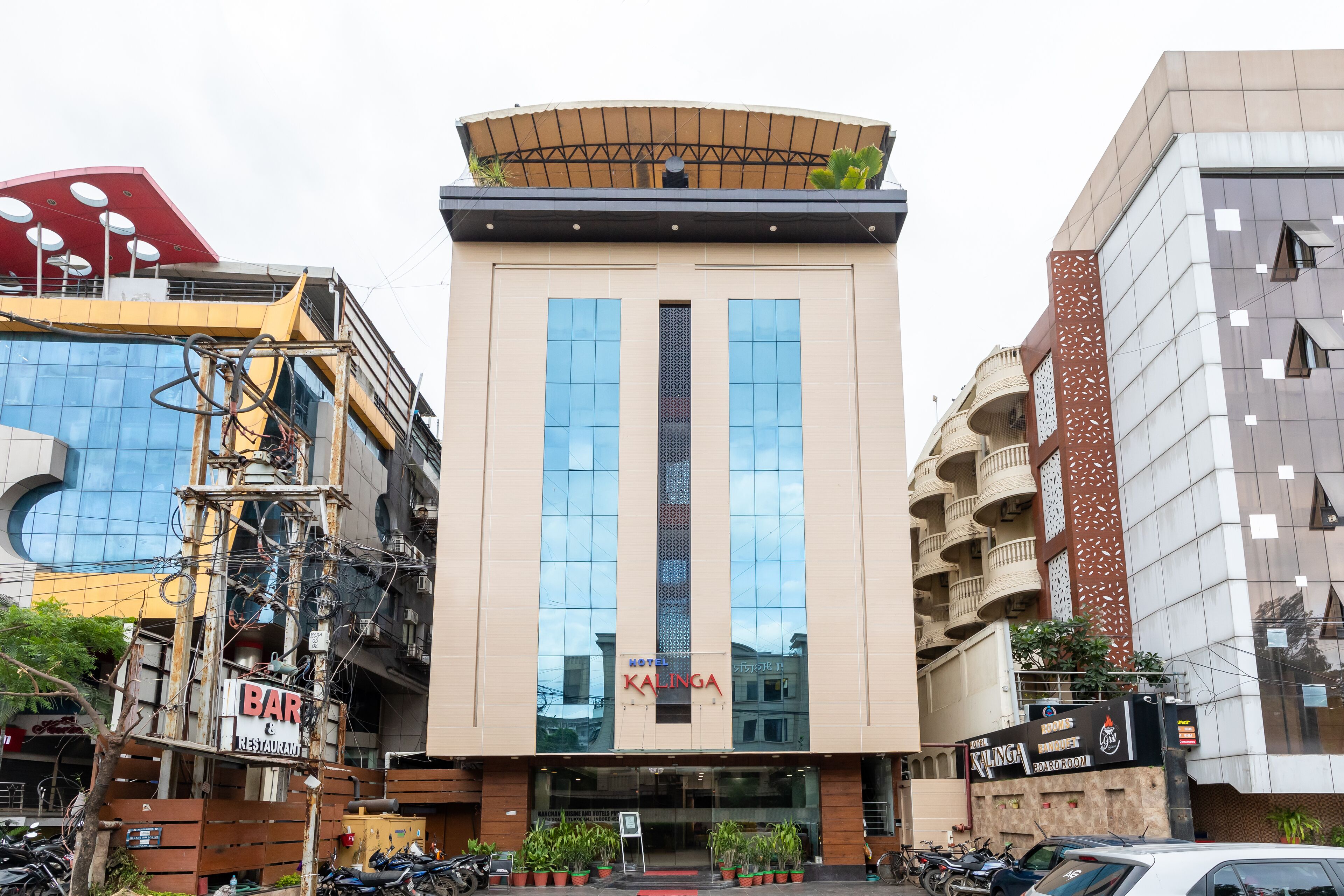 A modern building with a prominent 'KALINGA' sign, large windows, and a balcony with plants.