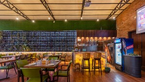 A restaurant with wooden flooring, green chairs, and a bar area with a Pepsi refrigerator. - HOTEL KALINGA (Indore)