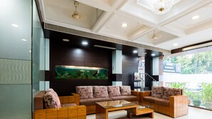 A modern lobby with a large aquarium, comfortable seating, and a view of the outside. - HOTEL KALINGA (Indore)