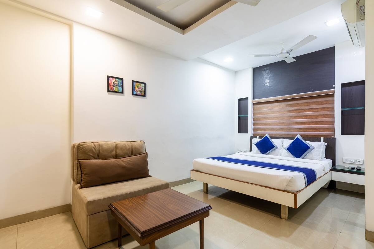 Un dormitorio con cama, sofá, mesita de noche y ventilador de techo.