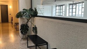 A modern interior with a large window, a plant, and a bench. - PlexiSpace (Athens)