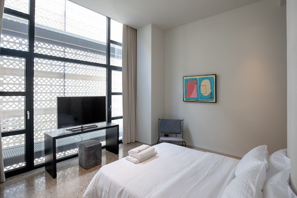 Una habitación de hotel con cama, televisor, escritorio y silla.