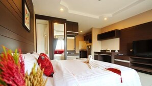 A hotel room with a large bed, a TV, a kitchenette, and a bathroom visible through an open door. - Valhalla Pattaya Hotel (Pattaya)