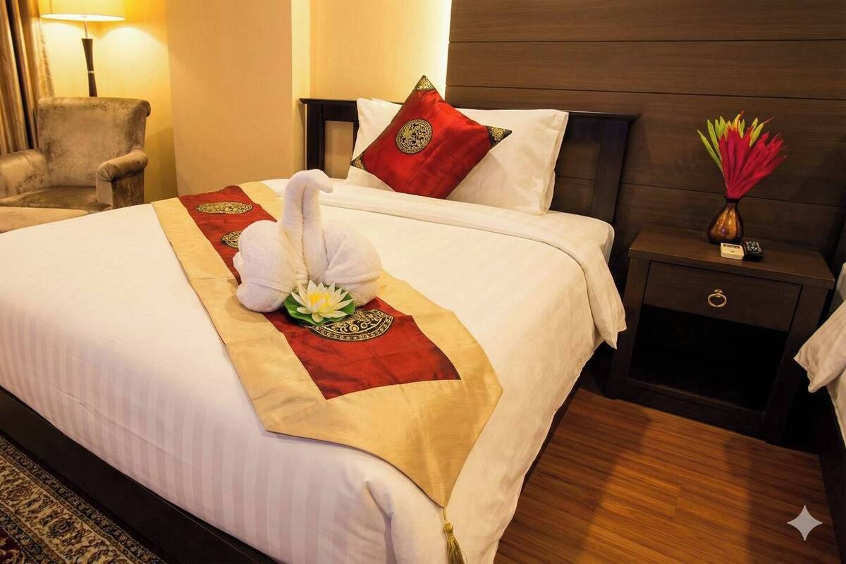 A hotel room with a bed, a chair, a nightstand, and a lamp.