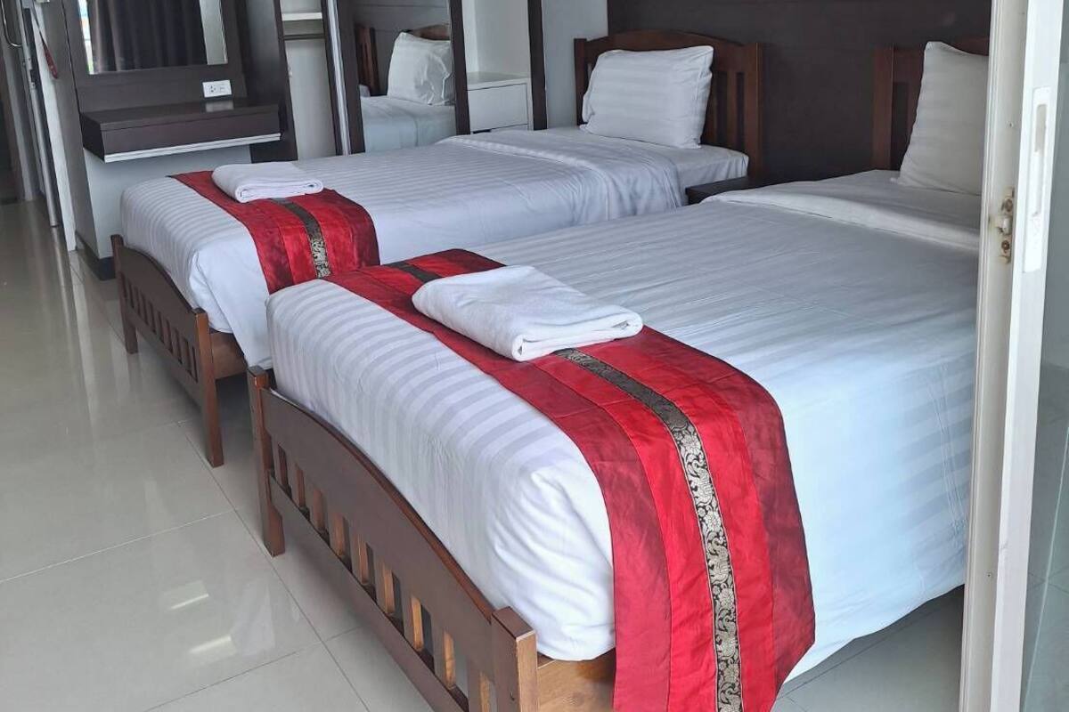 A hotel room with two beds, a large mirror, a painting, and a door leading to another room.