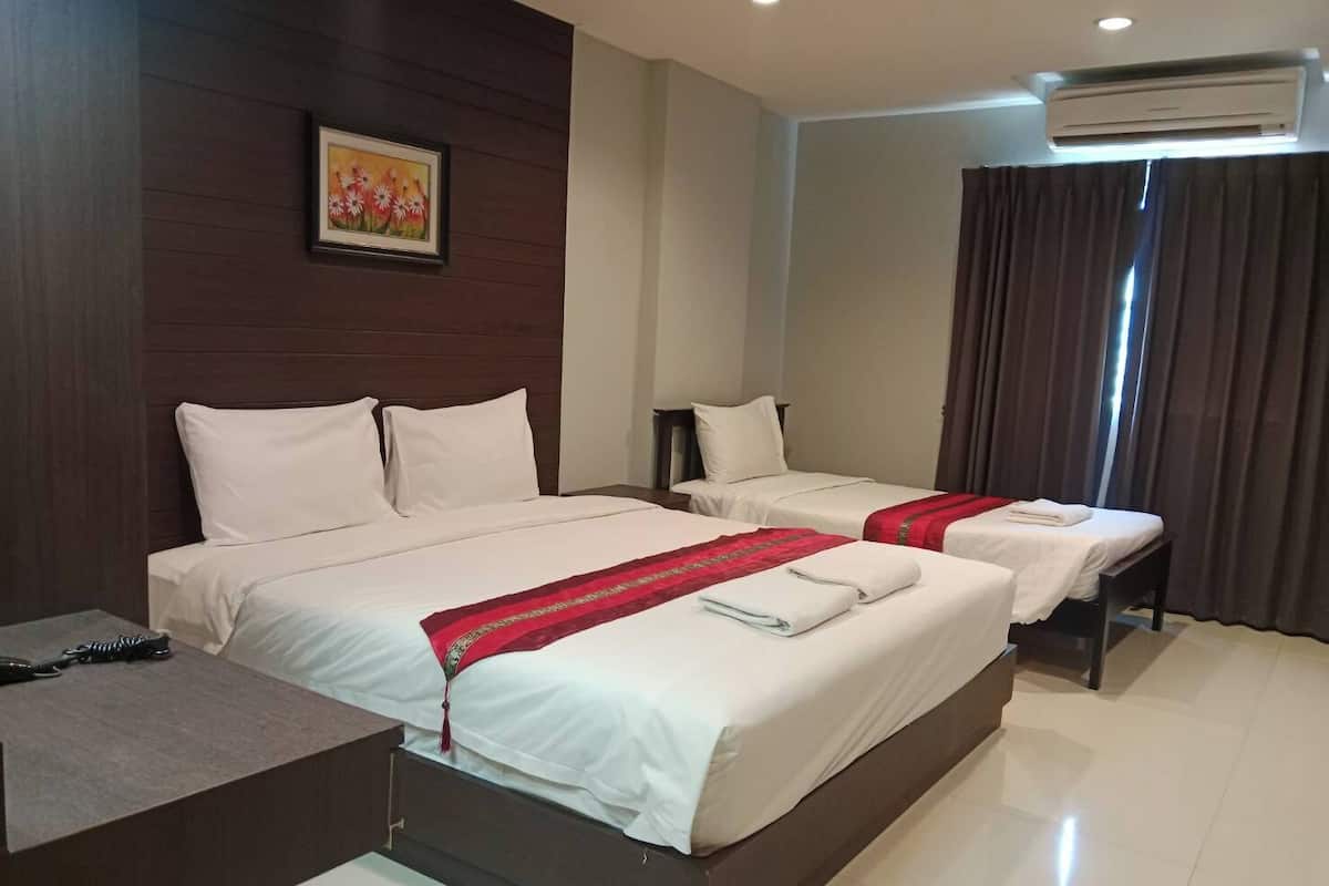 A hotel room with two beds, a desk, and an air conditioning unit.