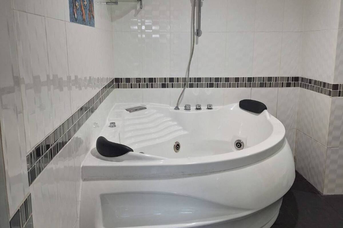 A modern bathroom with a large freestanding bathtub, a glass shower enclosure, and a mosaic tile border.