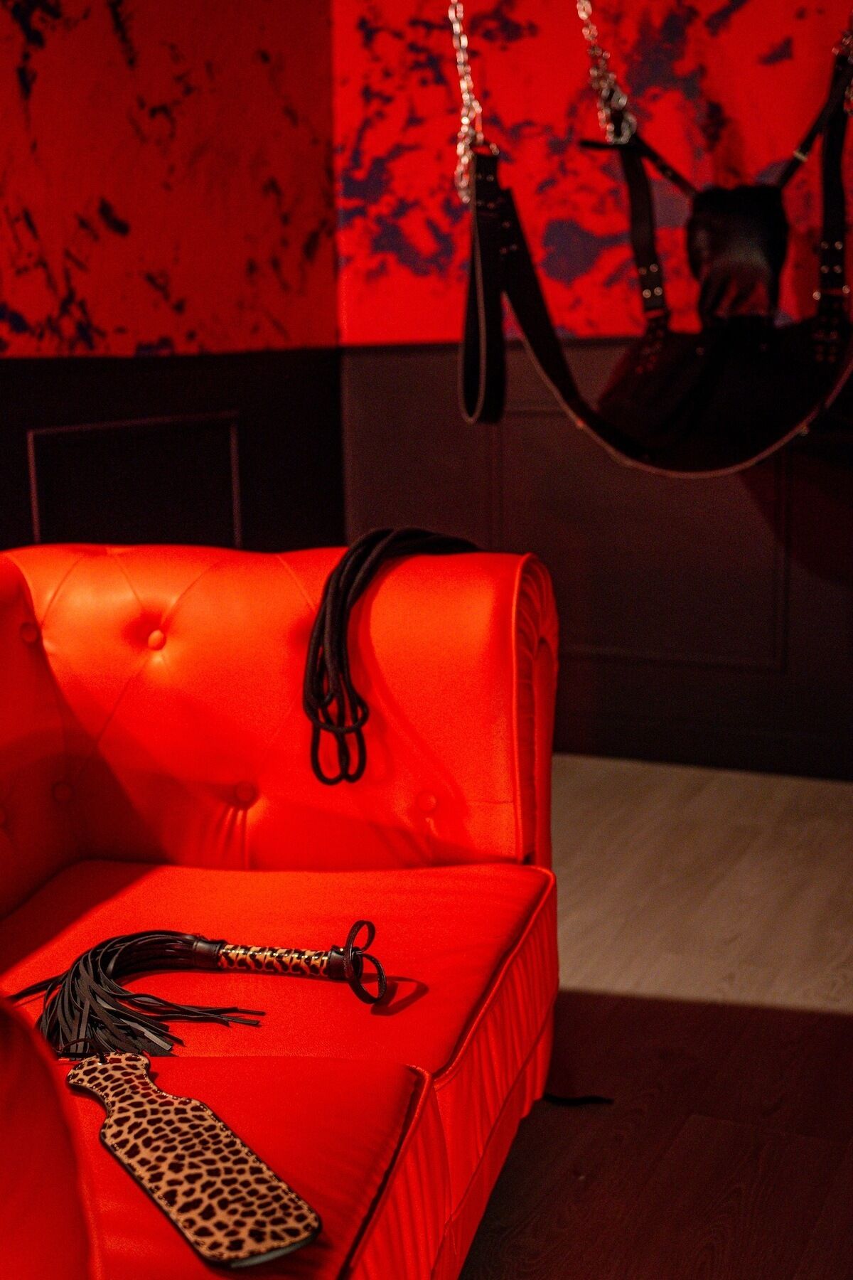 Un sofá rojo con un bolso estampado de leopardo y un cinturón de cuero negro.