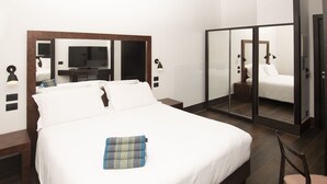 Une chambre d’hôtel avec un grand lit, une télévision, un miroir et un bureau.