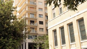 Un immeuble résidentiel à plusieurs étages, doté de balcons, avec une entrée bien visible et un arbre au premier plan.