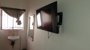 A bathroom with a sink, mirror, and a wall-mounted TV.