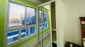 Una habitación con un ventanal grande, una puerta y una mesita.