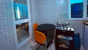Una cocina compacta con estufa a gas, una mesa de comedor con dos sillas y una ventana con vistas.