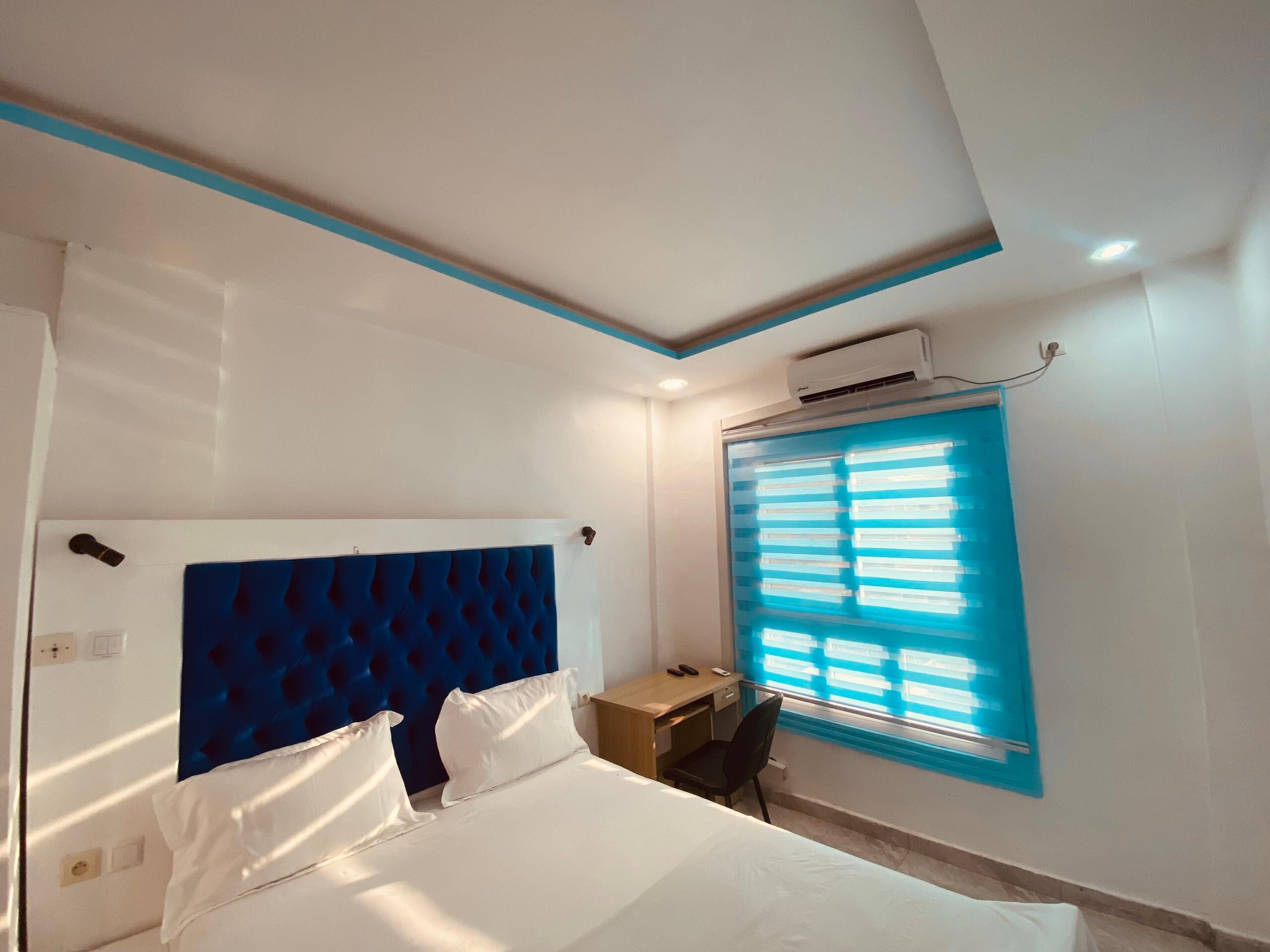 Una habitación de hotel con cama, escritorio y ventana con persianas.