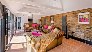 A spacious living area with a high ceiling, a brick wall, and a large sofa set. - The Willows -  a holiday let by Bloom Stays that sleeps 8 guests  in 4 bedrooms (Ash)
