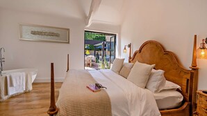 A bedroom with a large bed, a wooden headboard, a bedside table with a lamp, and a framed picture on the wall. - The Willows -  a holiday let by Bloom Stays that sleeps 8 guests  in 4 bedrooms (Ash)