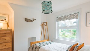 Une chambre à coucher avec un lit, une commode en bois et une fenêtre donnant sur un paysage verdoyant.