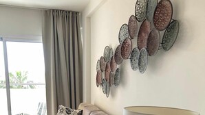 A living room with a sofa, a patterned lamp, and a wall art piece. - Luxury Apartment in Club Playa Flores (Torremolinos)