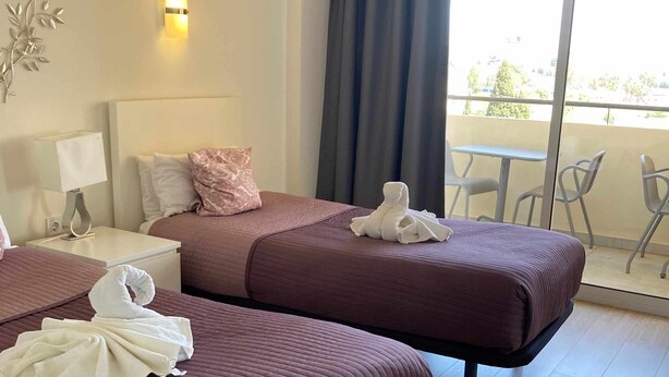 Une chambre d’hôtel avec deux lits, un balcon et une vue sur l’extérieur.