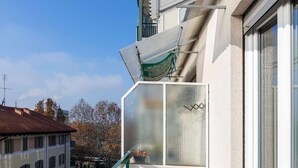 A balcony with a wooden floor, white railings, and a view of the cityscape. - [Lingotto - Inalpi Arena] Bright Apartment (Torino)