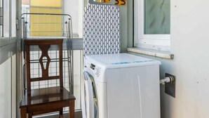 A laundry area with a washing machine, a drying rack, and a chair. - [Lingotto - Inalpi Arena] Bright Apartment (Torino)