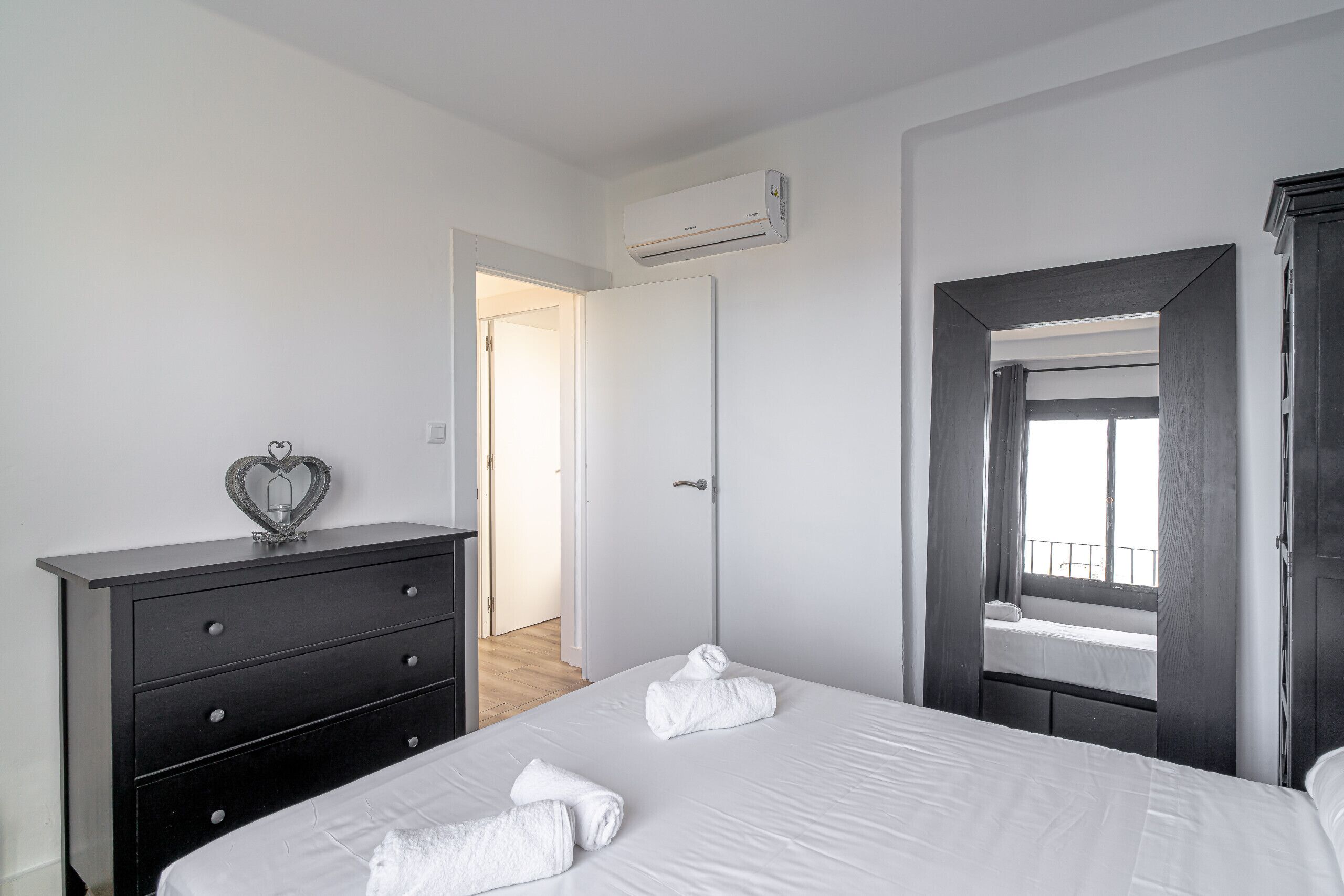 Ein Schlafzimmer mit einem Bett, einem Schminktisch, einer Klimaanlage und einem Fenster mit Blick.