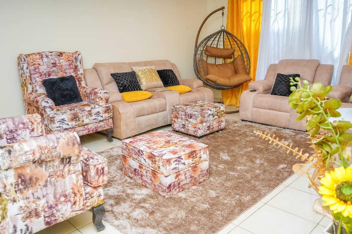 A living room with a sofa, two armchairs, a hanging chair, and matching ottomans.