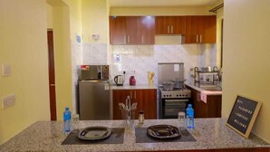 A kitchen with granite countertops, stainless steel appliances, wooden cabinets, and a sign indicating WiFi availability. - Lux Suites Greatwall Getaway Apartments (Athi River)