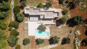 An aerial view of a modern house with a swimming pool, surrounded by trees and a rocky landscape. - Villa La Guaceta by Wonderful Italy (Carovigno)