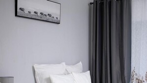 A hotel room with two beds, a grey headboard, white bedding, a grey curtain, and a framed picture on the wall. - Semeni Asante Getaway (Johannesburg South)