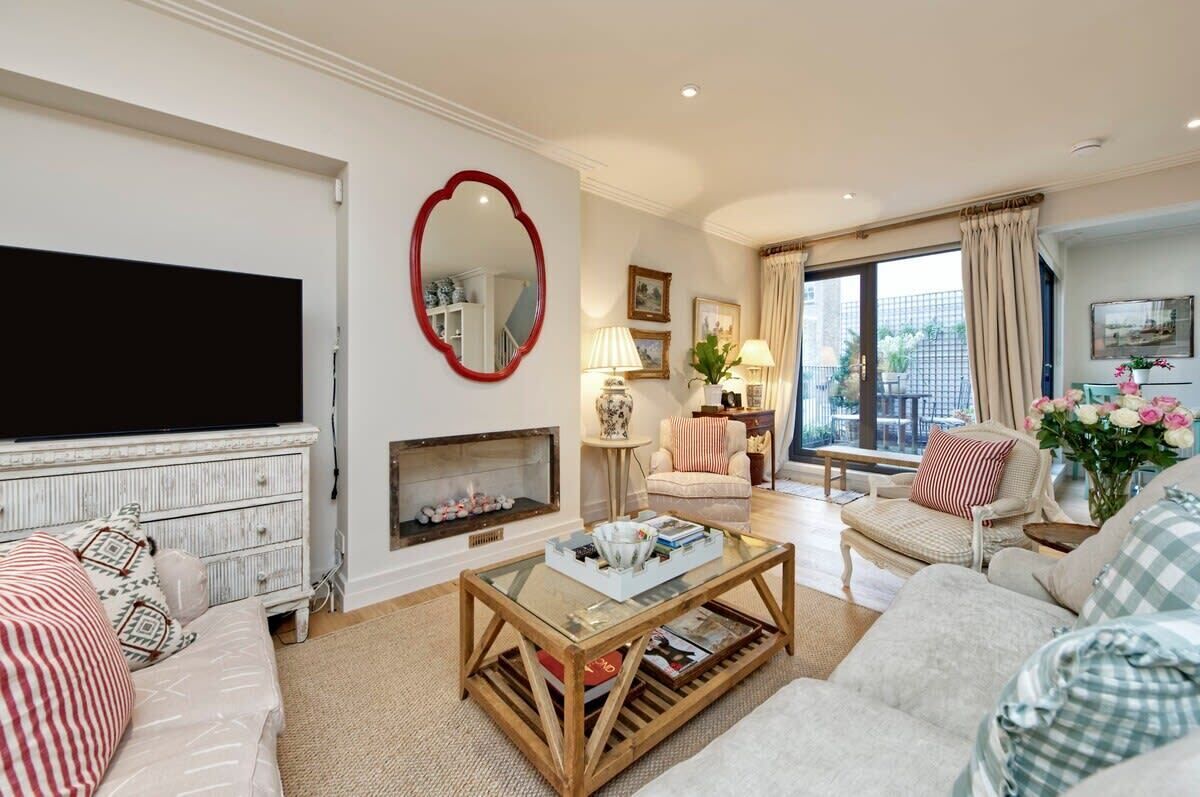 A living room with a fireplace, a television, and a large window with curtains.