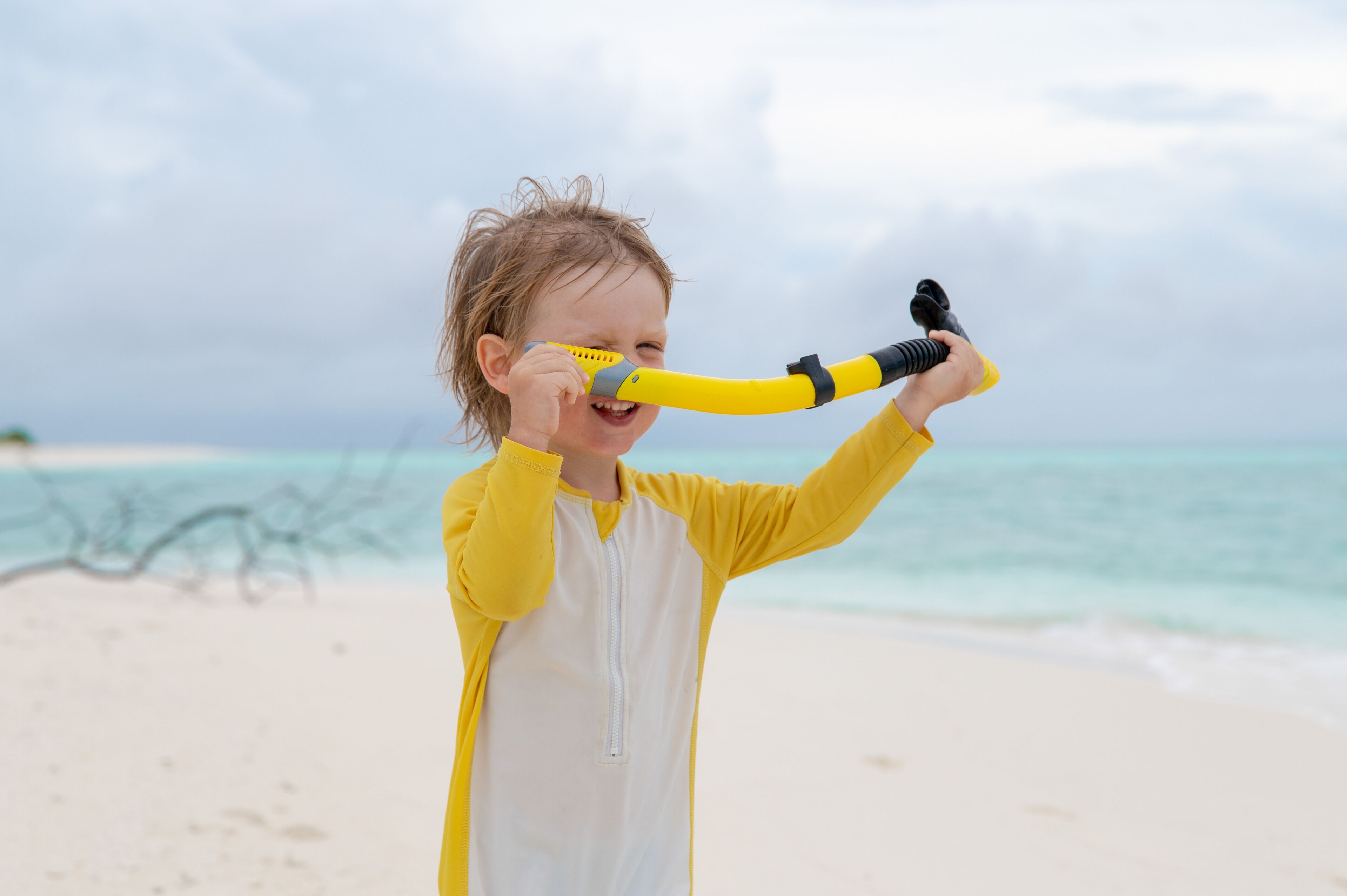 Een kind op het strand met een geel en zwart speeltje.