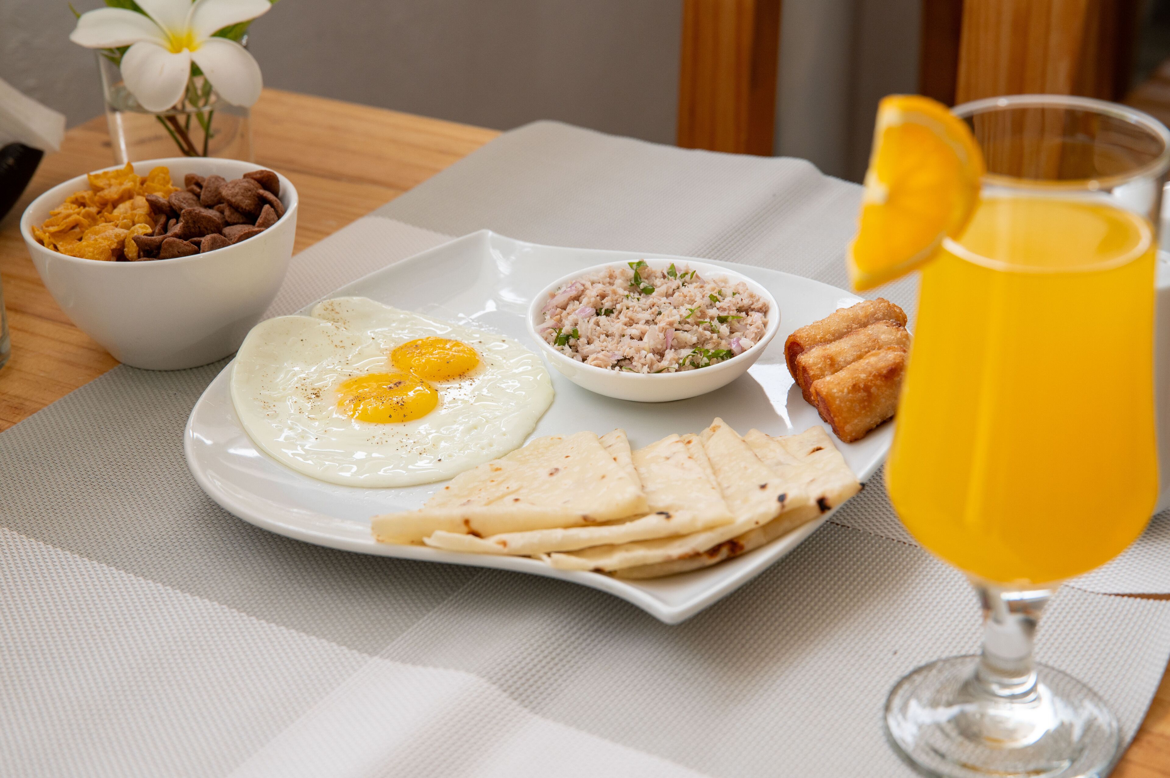 A breakfast plate with eggs, rice, and bread, accompanied by a glass of orange juice.