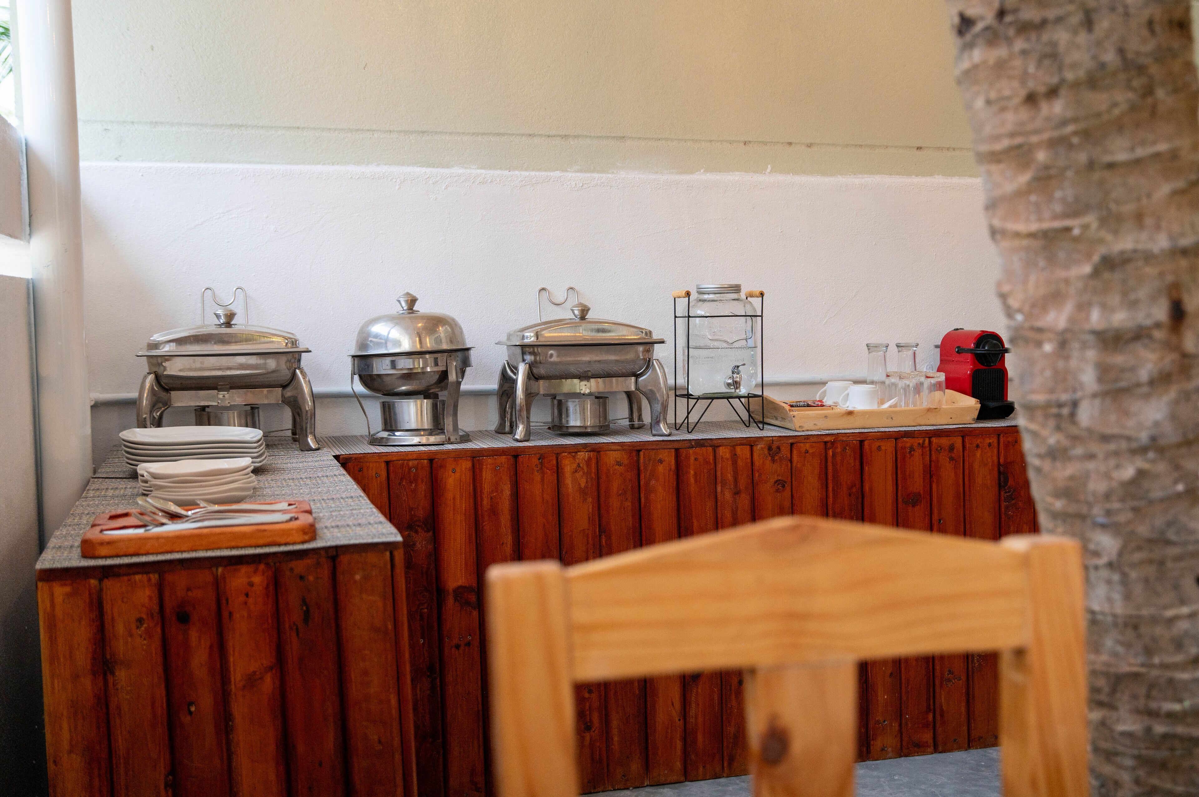 Een buffetopstelling met verschillende voedselcontainers, een waterdispenser en een koffieapparaat.