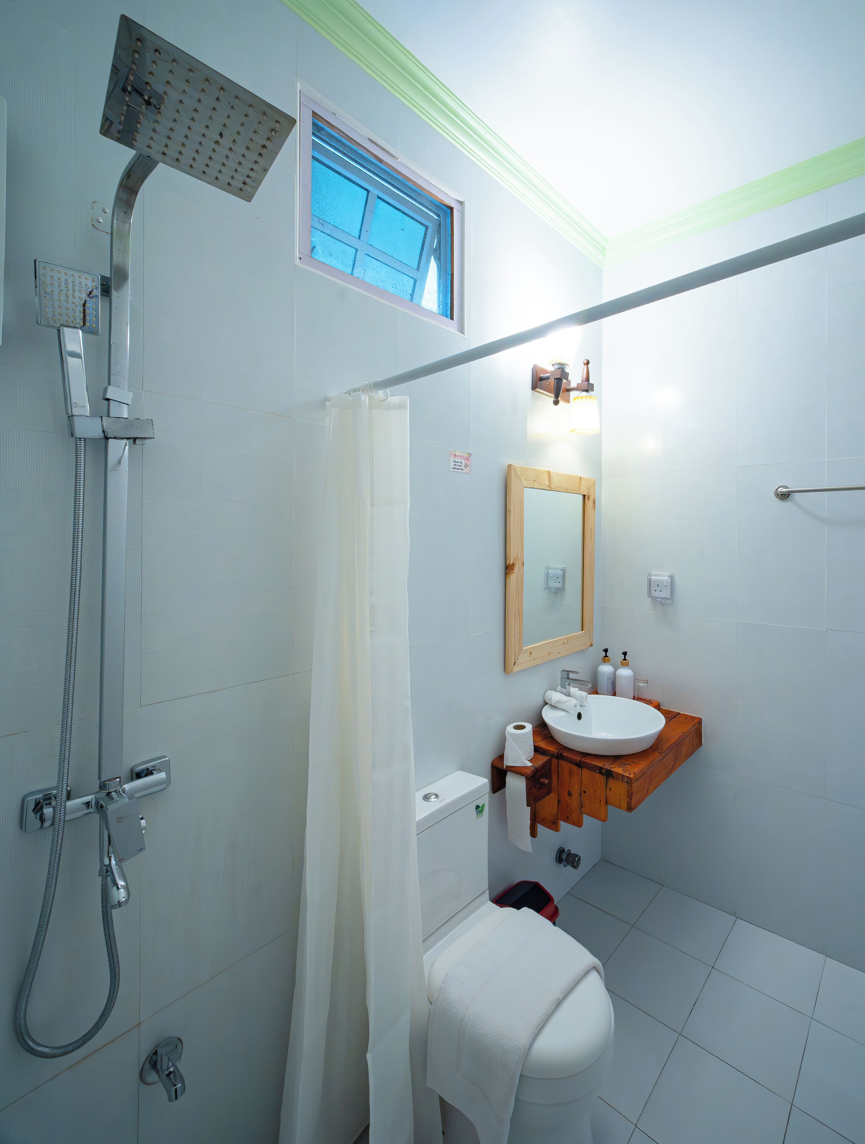A bathroom with a shower, toilet, sink, and a window.